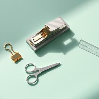 Compact stapler and brass clips on ivory paper