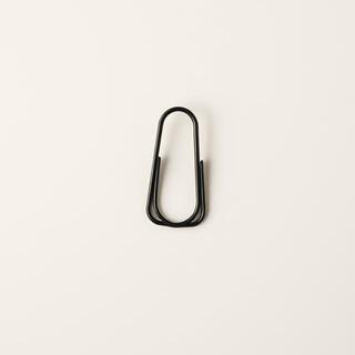 Black wire clip gripping a small note